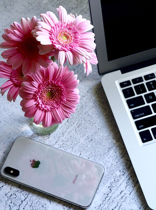 A laptop computer and a vase of daisies on a table