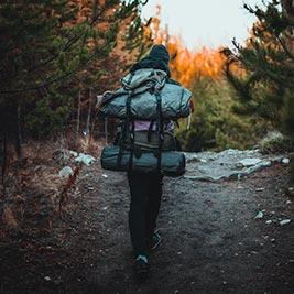 A woman hiking in the woods wearing a backpack