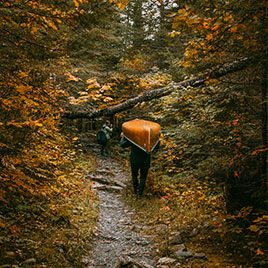 A person carrying a canoe in the woods