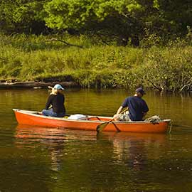Two people paddling on the water in an orange canoe